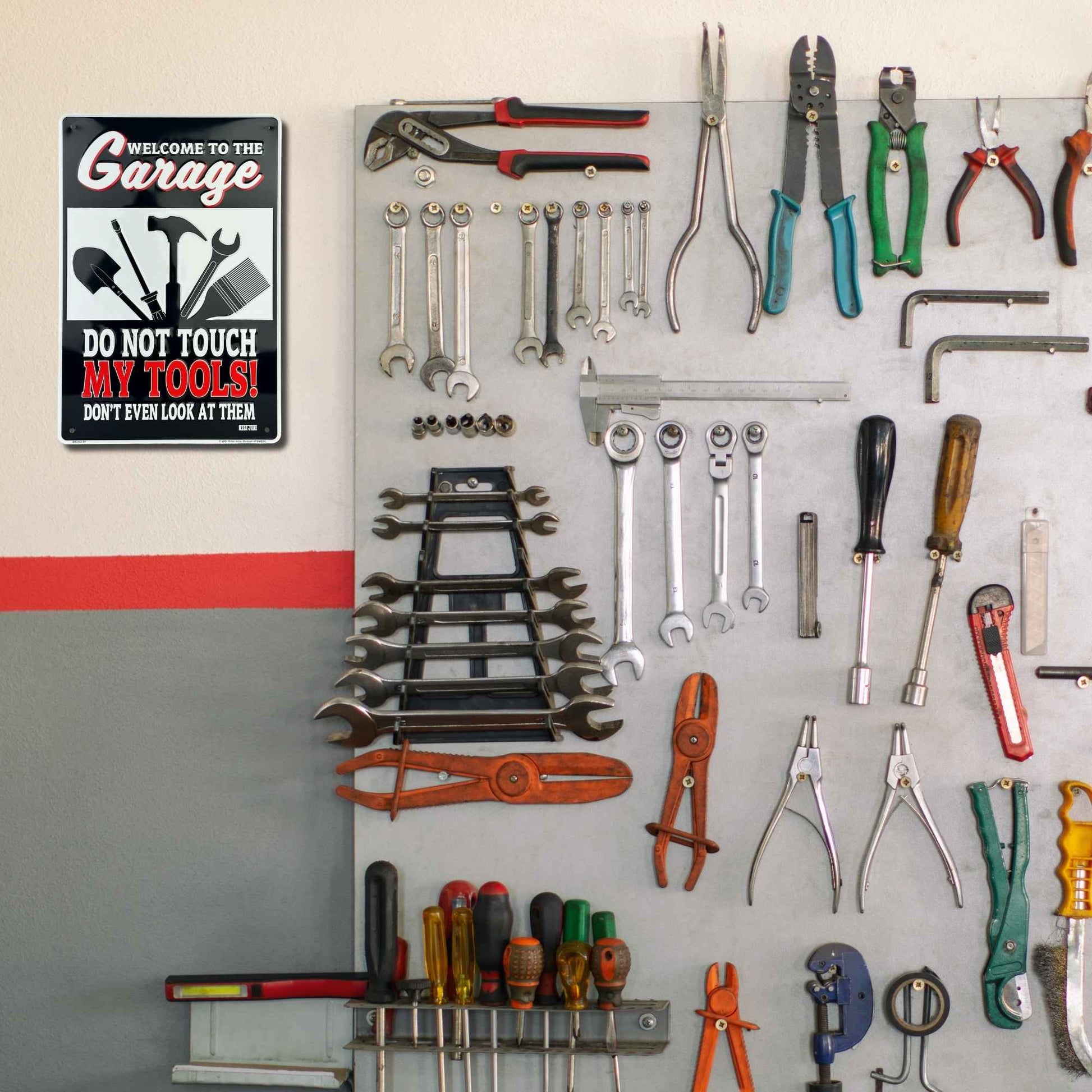 Wall-mounted tool organizer with various tools on a gray pegboard against a white wall.