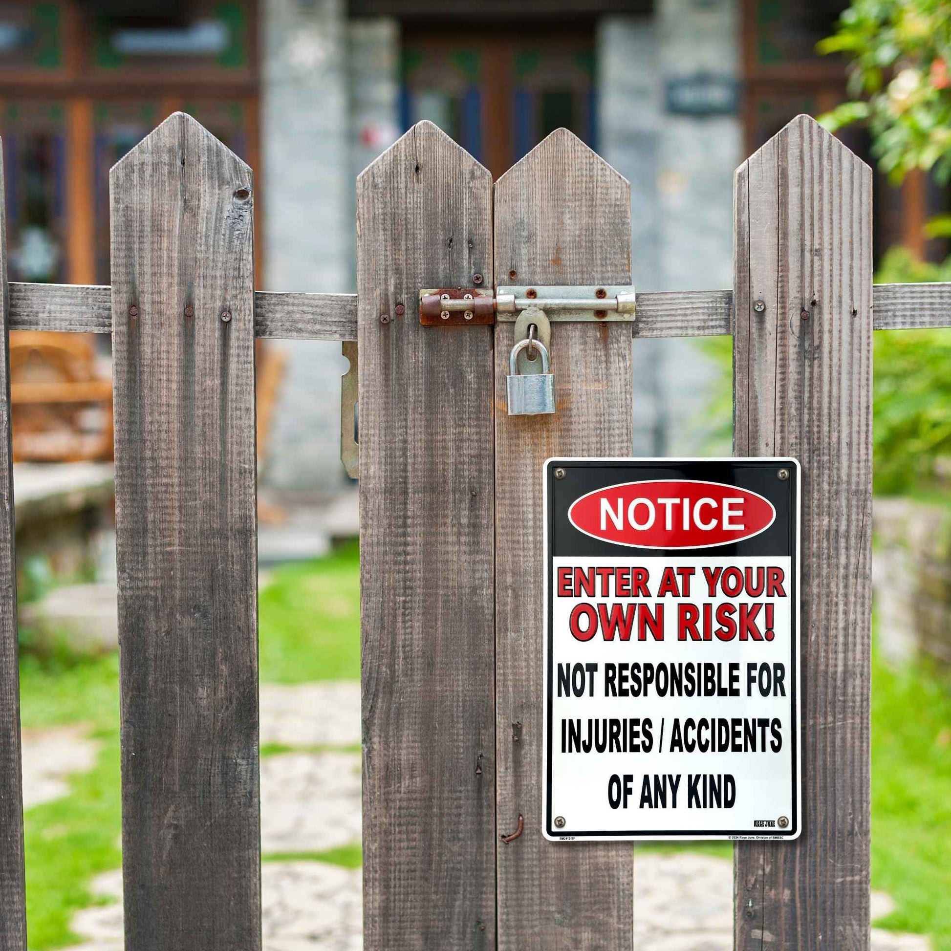 Wooden fence with a warning sign attached, set against a blurred outdoor background.