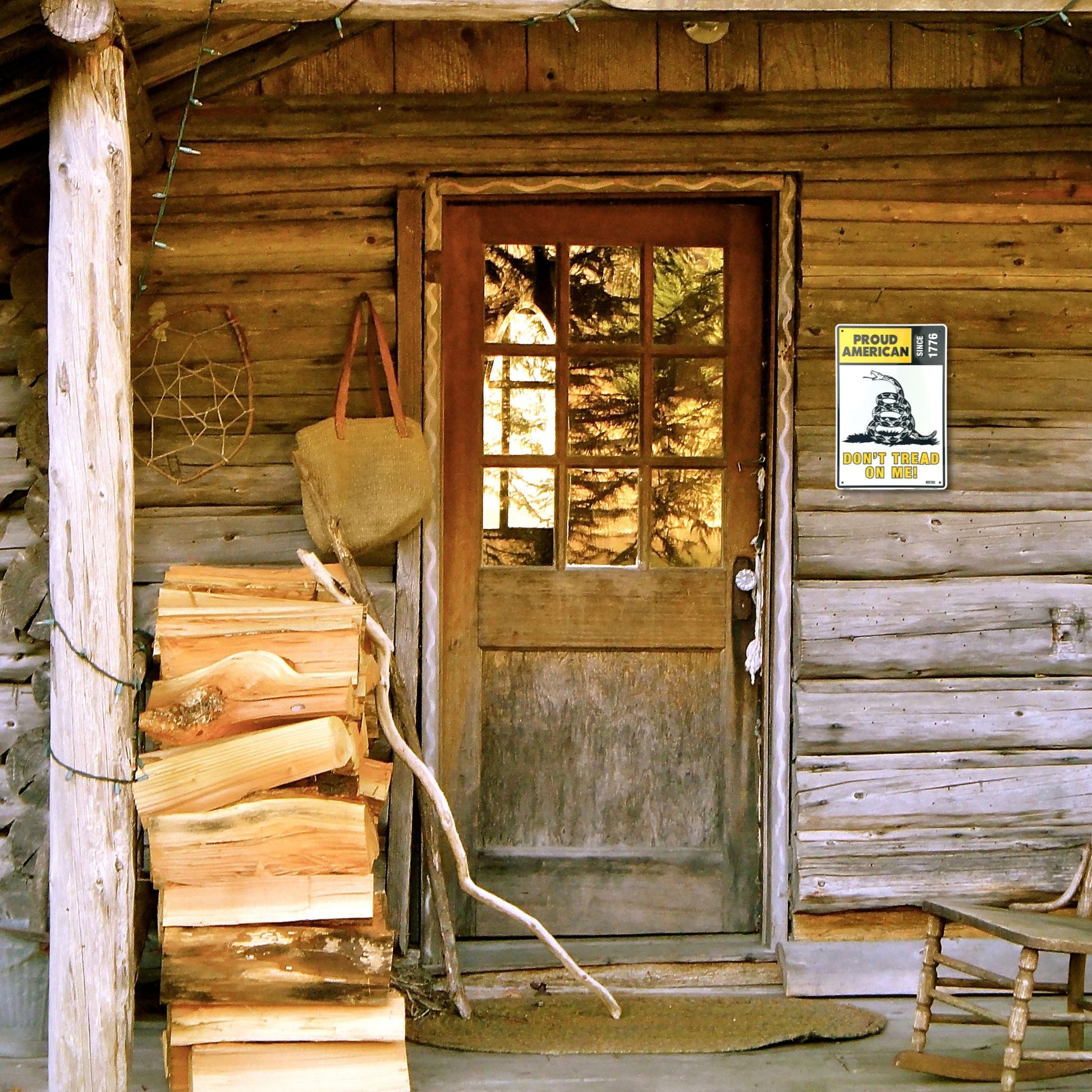 Wooden cabin entrance with logs stacked against the wall and a sign on the door. BM2424-SP