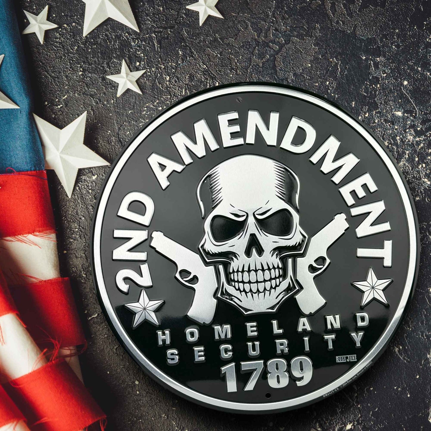 Circular emblem with '2nd Amendment Homeland Security 1789' text, skull, and crossed guns on a dark background with American flag and stars.