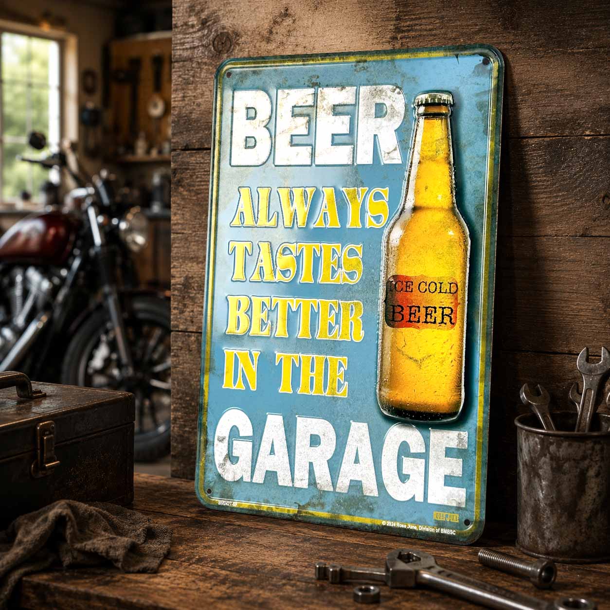 Metal sign with beer bottle graphic and text 'Beer always tastes better in the garage' on a wooden background.