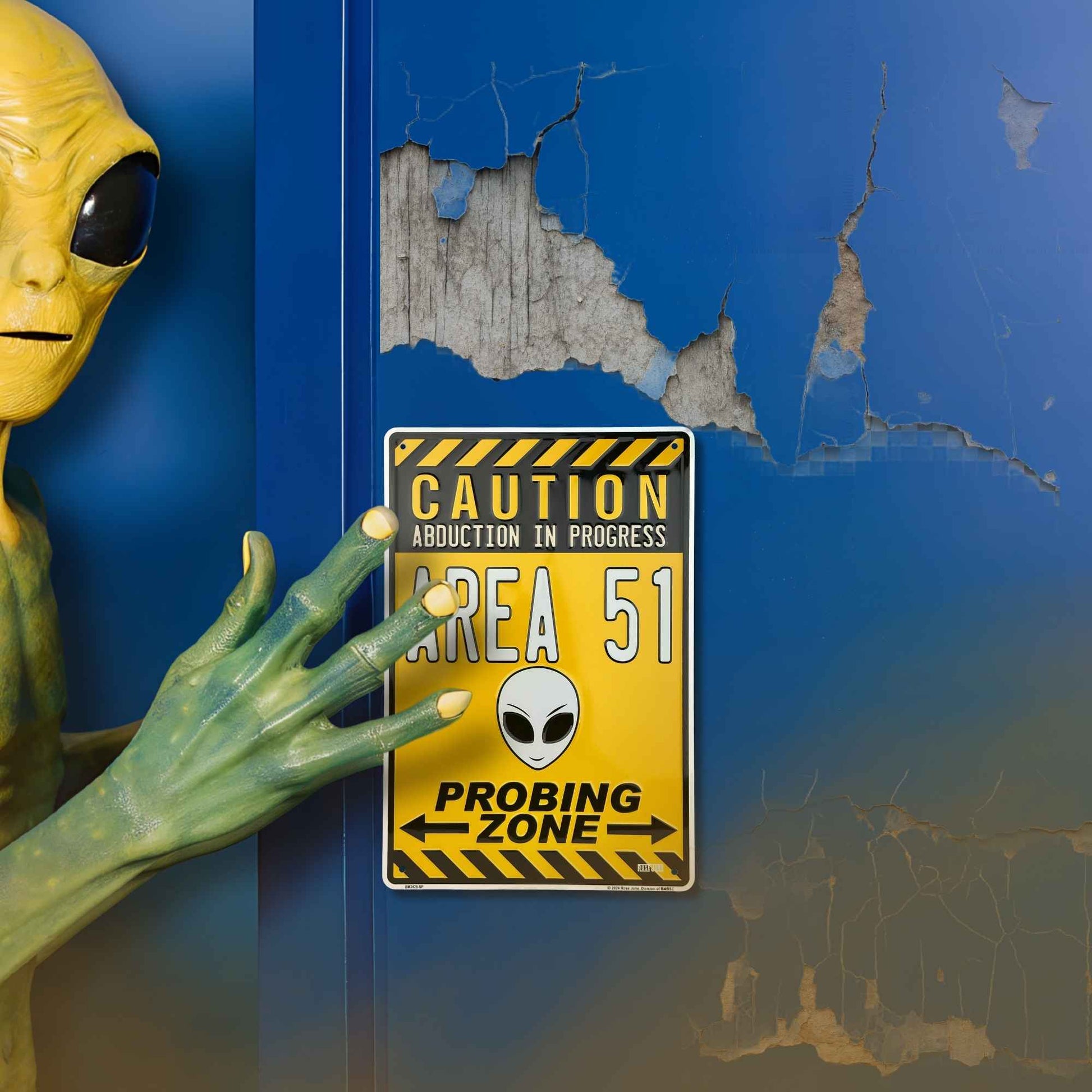 Alien figure next to a 'Caution: Area 51' sign on a blue wall with peeling paint.