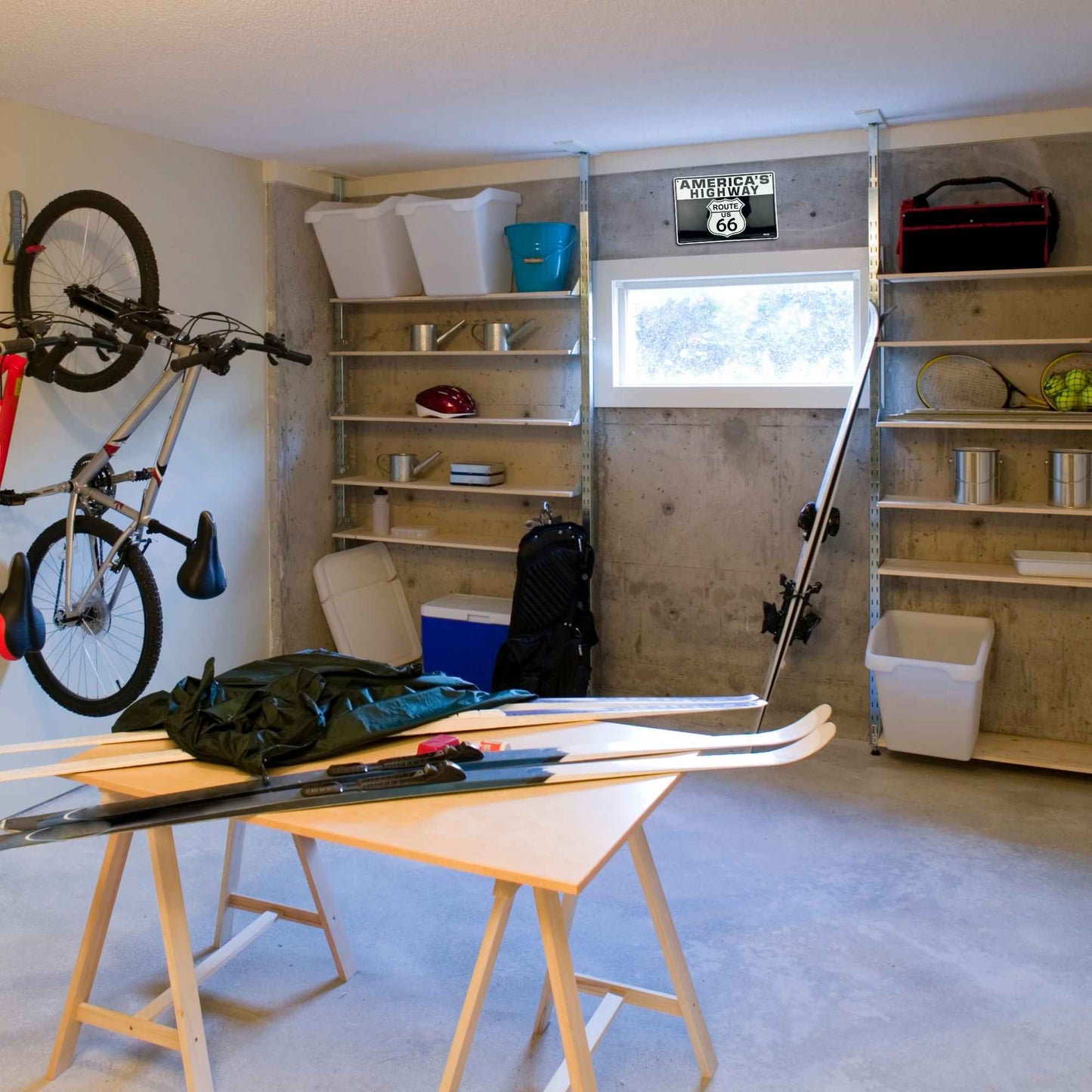 Garage with shelves, a bike, and various items including skis on a table.