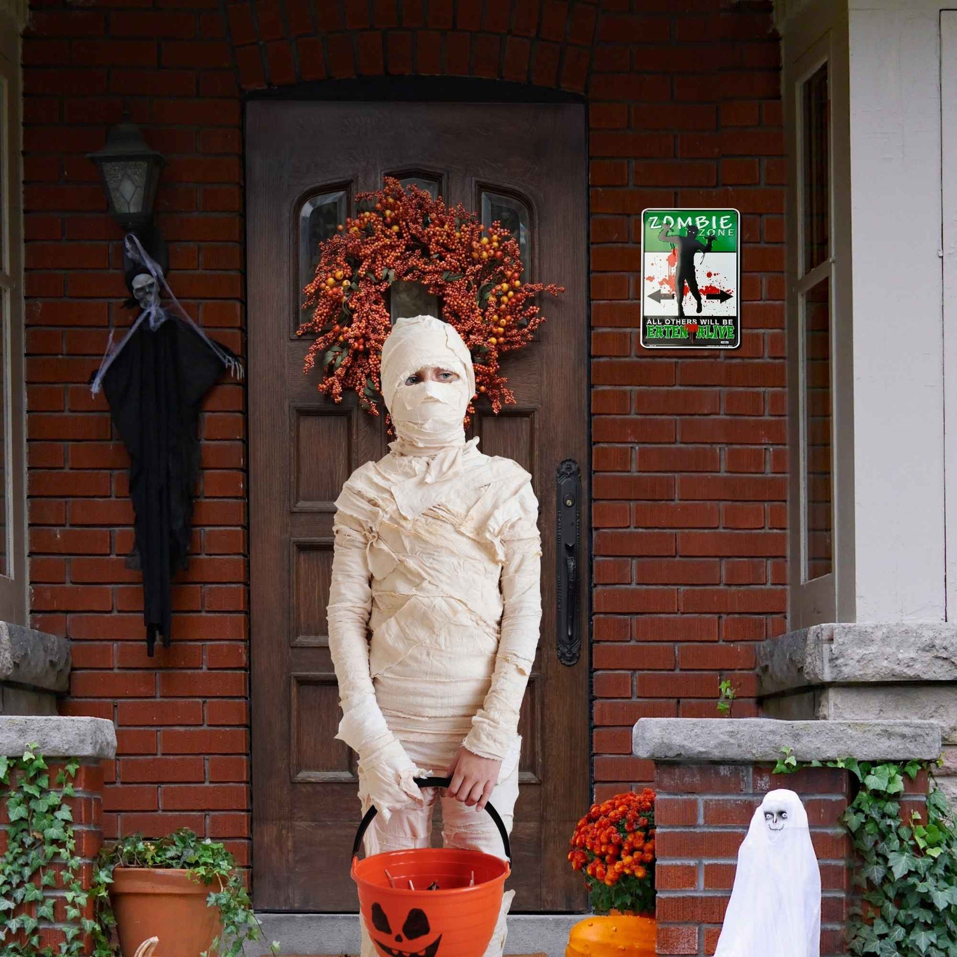 Person in a mummy costume standing in front of a house with Halloween decorations.