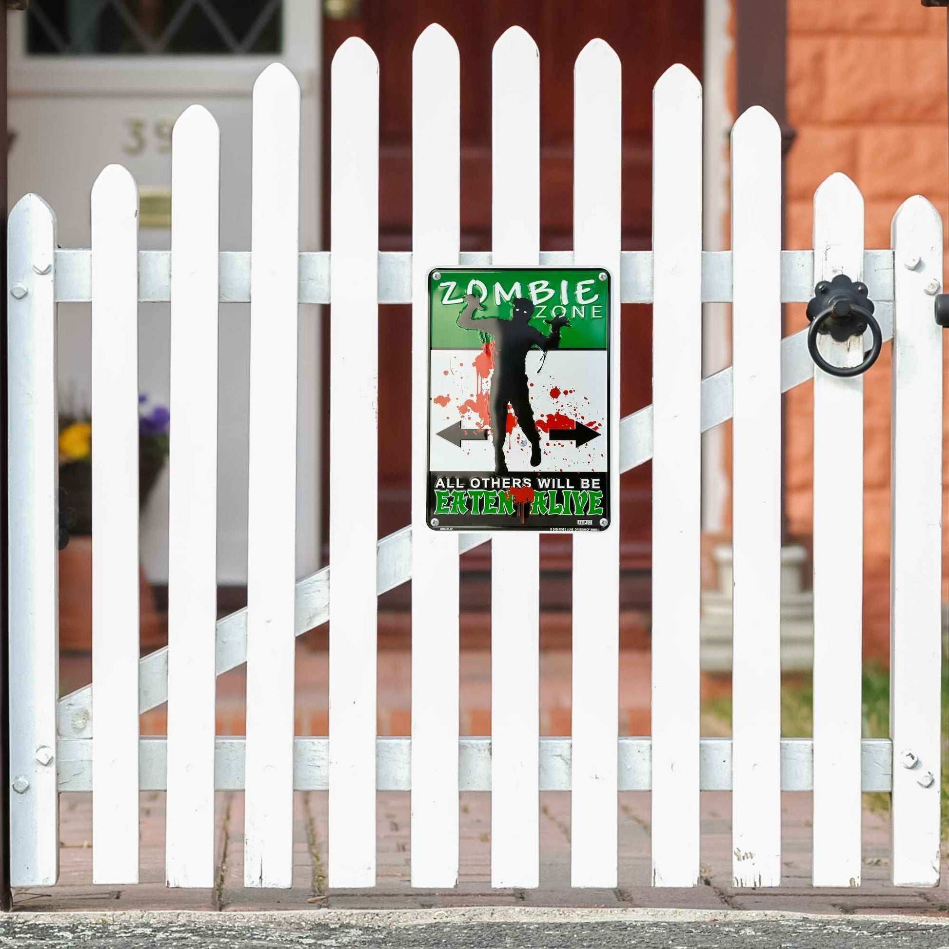 Zombie zone sign on a white picket fence with a house in the background