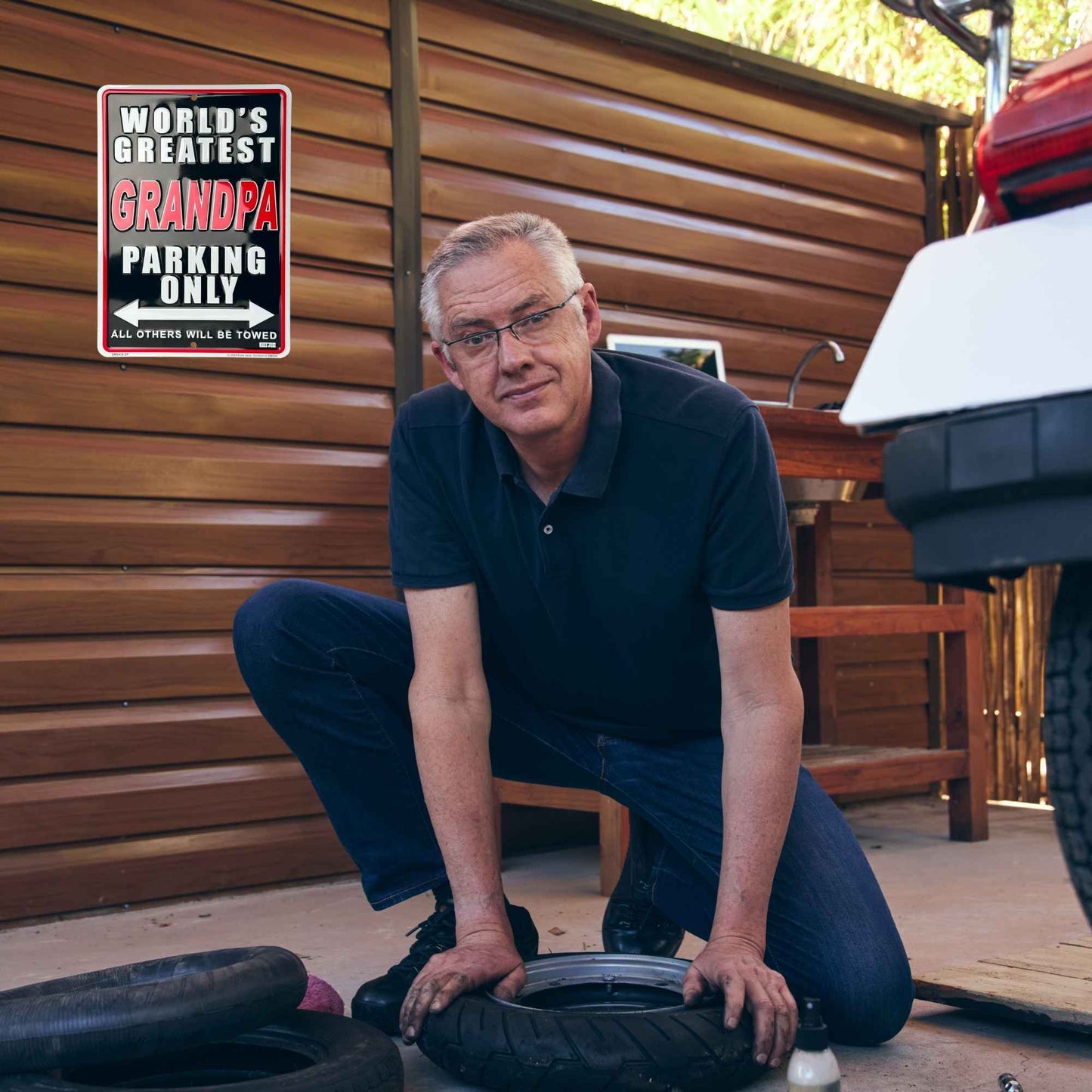 World's Greatest Grandpa parking only all others will be towed guy working on tire