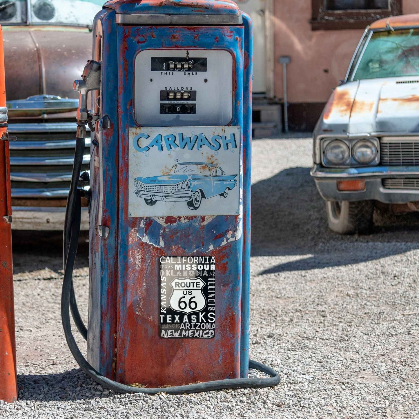 Vintage gas pump with Route 66 and carwash signs in a rustic setting.