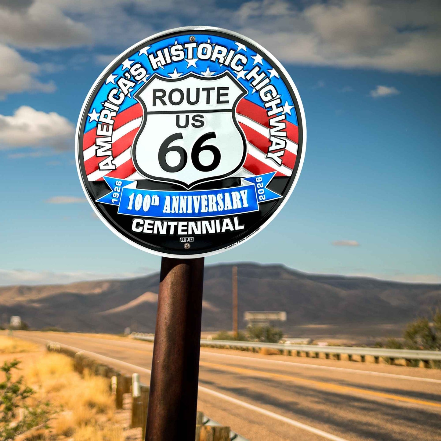 Route 66 sign with a scenic road and mountains in the background