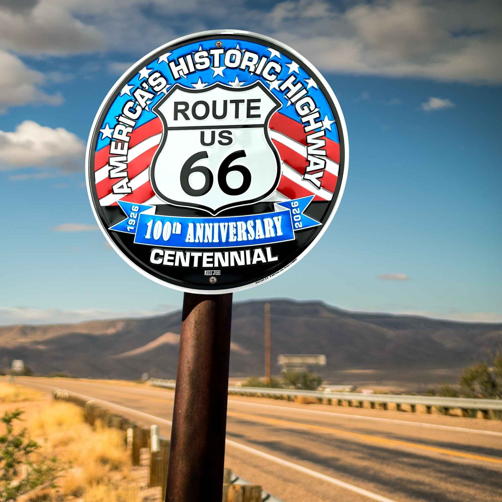 Route 66 sign with a scenic road and mountains in the background